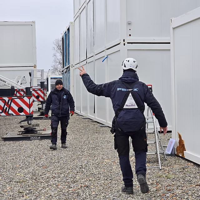 FERIZ-Mitarbeiter zwischen gelagerten Containern